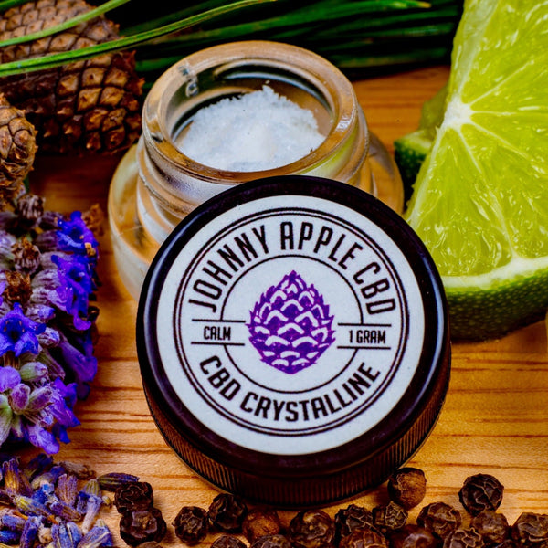 Johnny Apple CBD Calm Soothing crystalline jar beside an open jar of crystals, with lavender, pine cones and lime